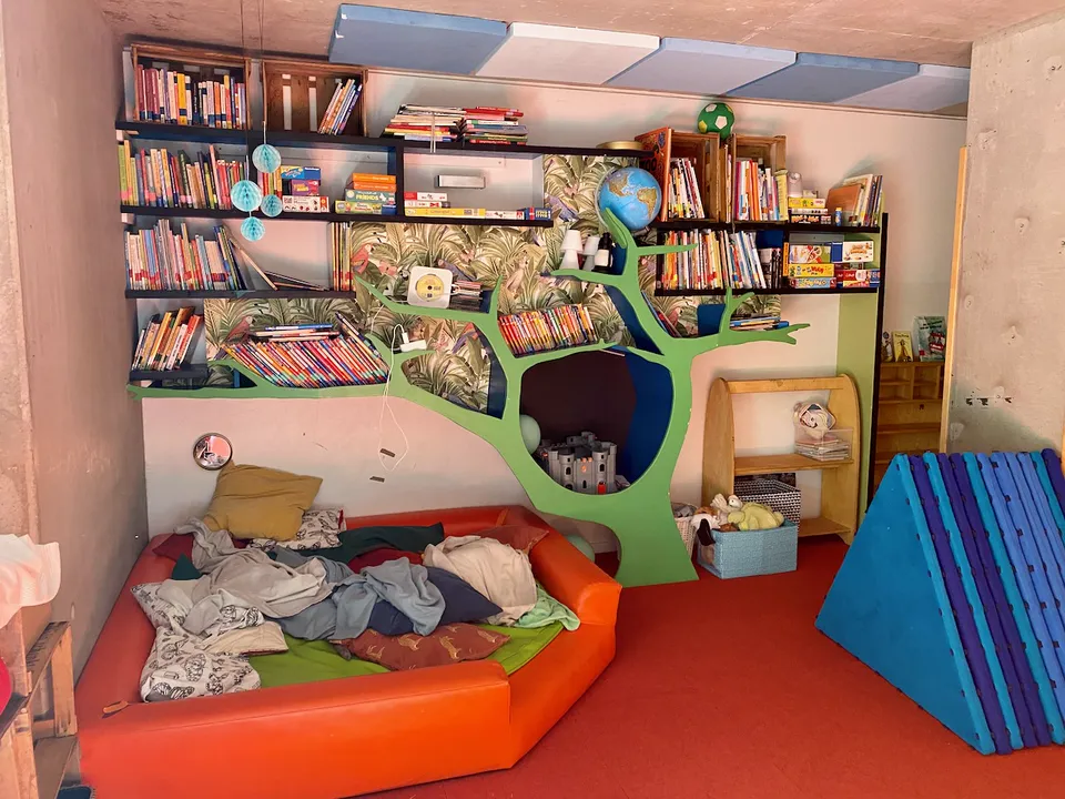 Gemütliche Leseecke mit Bücherregal in Baumform und orangefarbenem Sofa